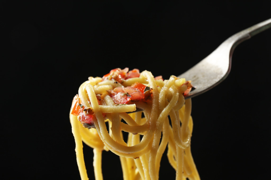 Italian pasta spaghetti on fork on black background