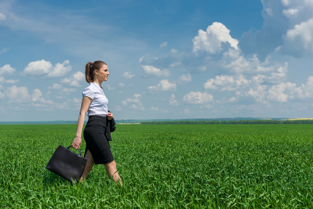 girl with a briefcase walking on green grass field