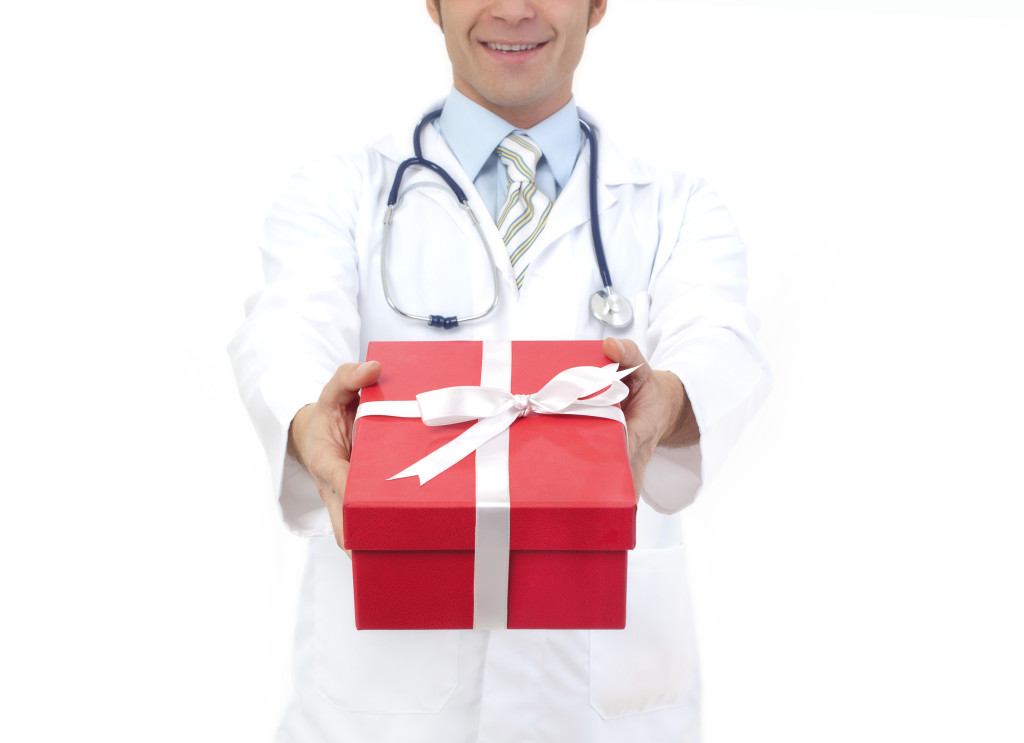 medical doctor holding gifts in hands isolated on white